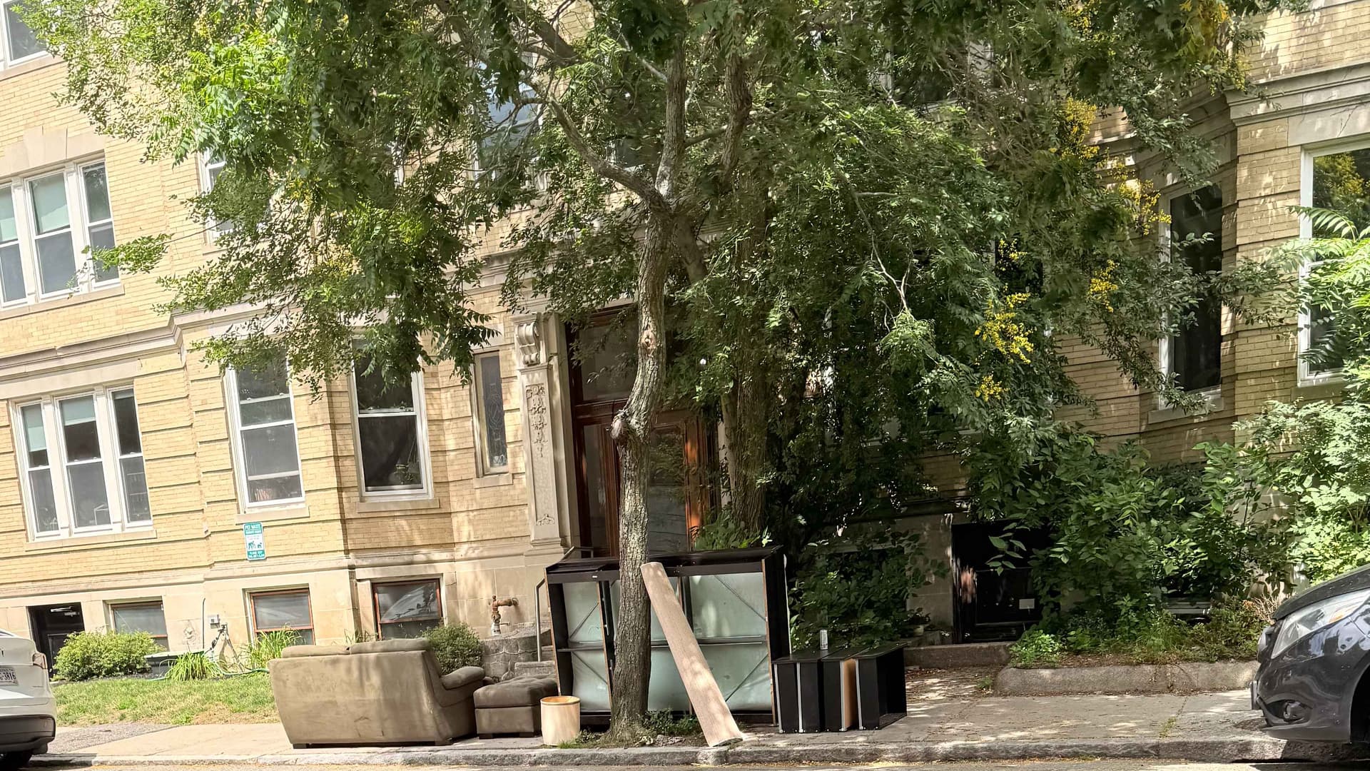 An apartment building with furniture at the side of the road