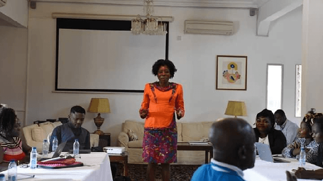 Arrey having a discussion with people with varied disabilities looking on. She has an orange dress on.