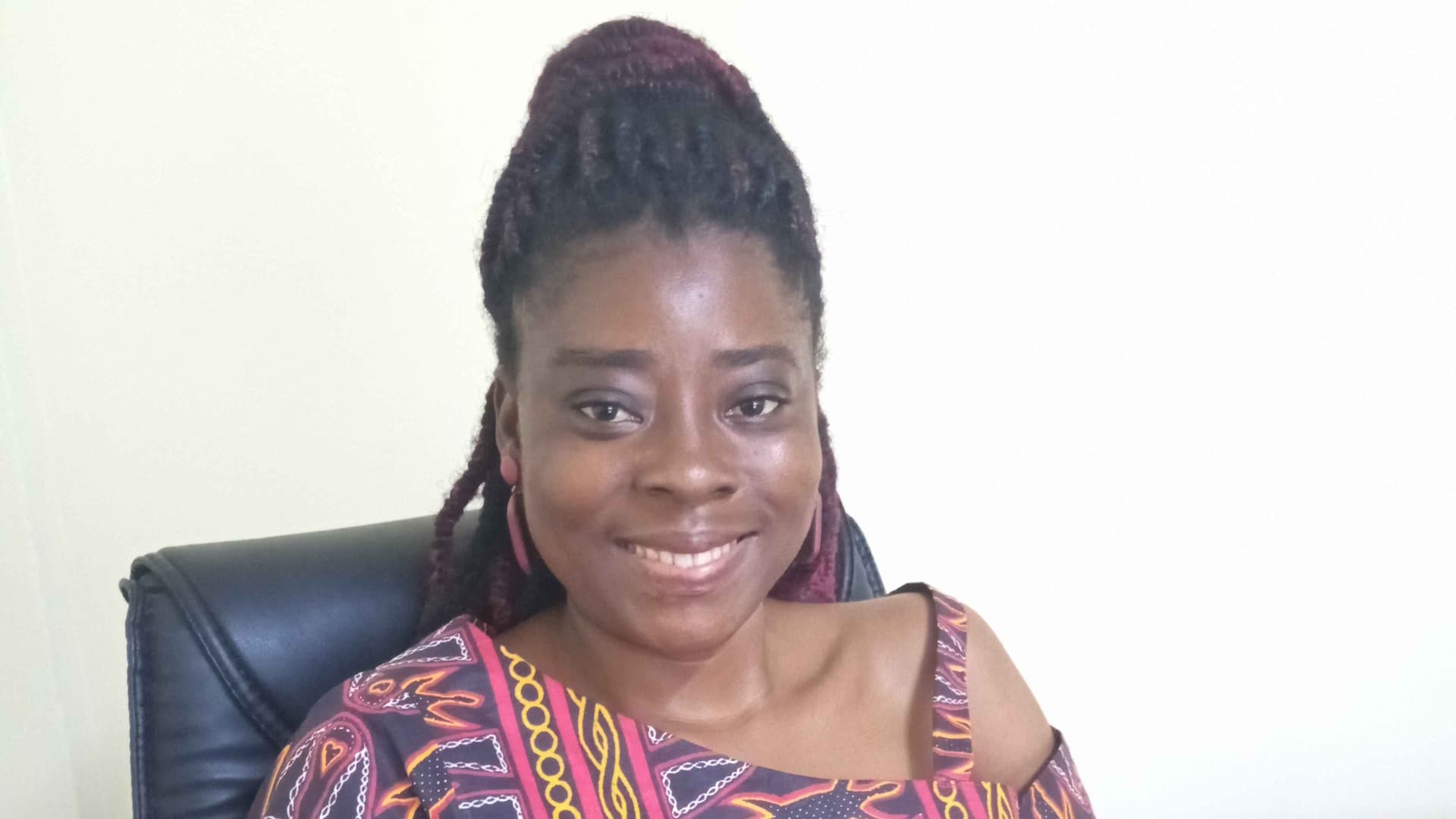 I am sitting in my office conference room, during one of my #BreakTheSilence colour awareness campaign. I have on a beautiful traditional Cameroon dress known as toghu in colours of red, black, orange, white and yellow. with my signature smile on.
