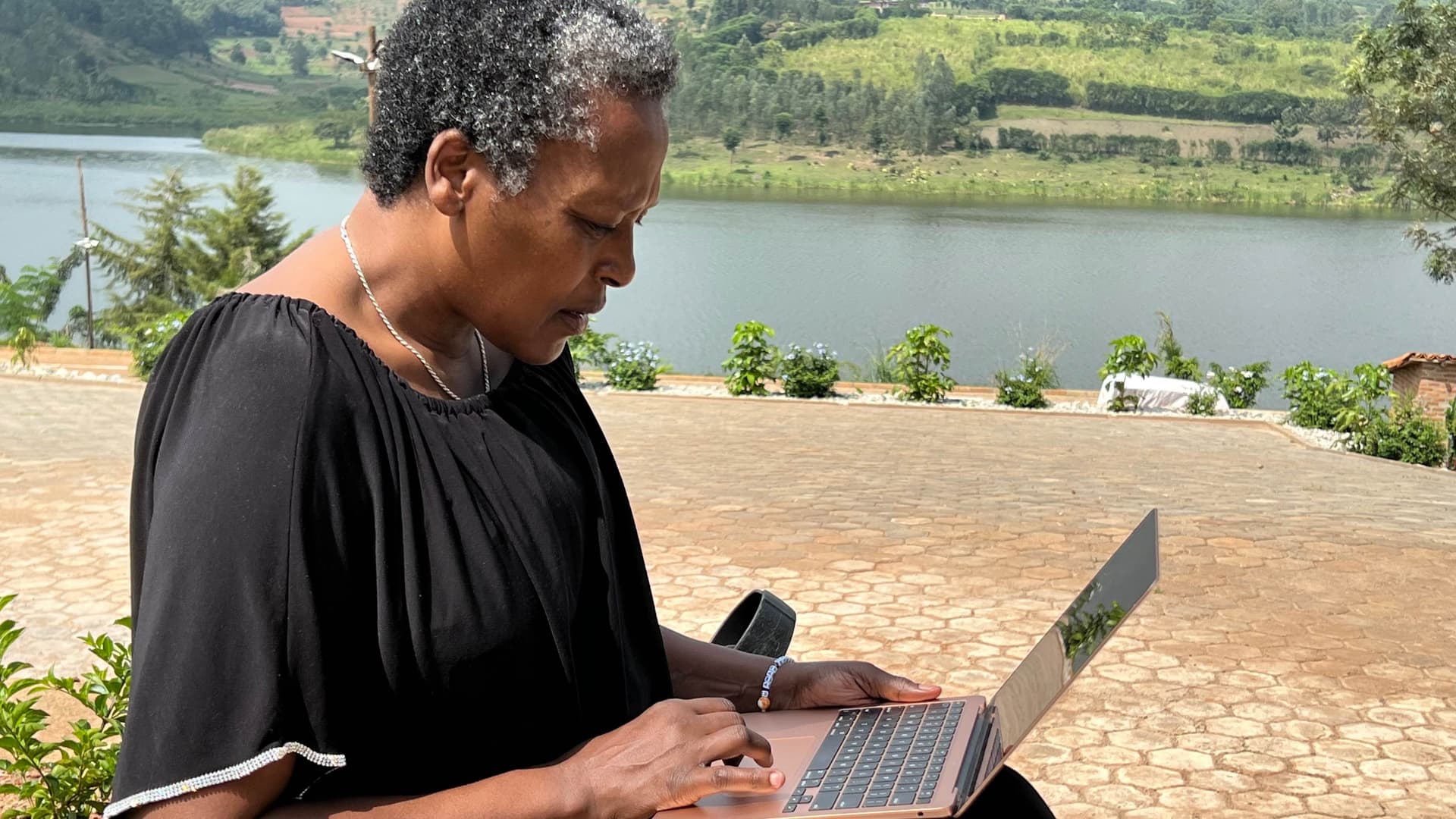 Neema on laptop sitting by lake